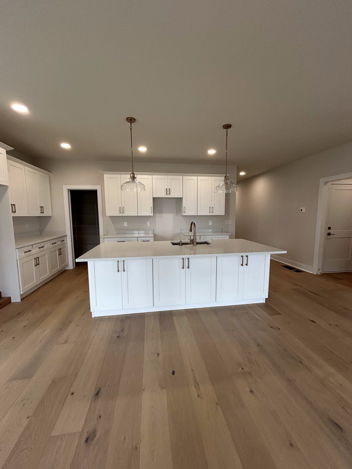 Model 1 kitchen with white cabinets, large island, and wood flooring