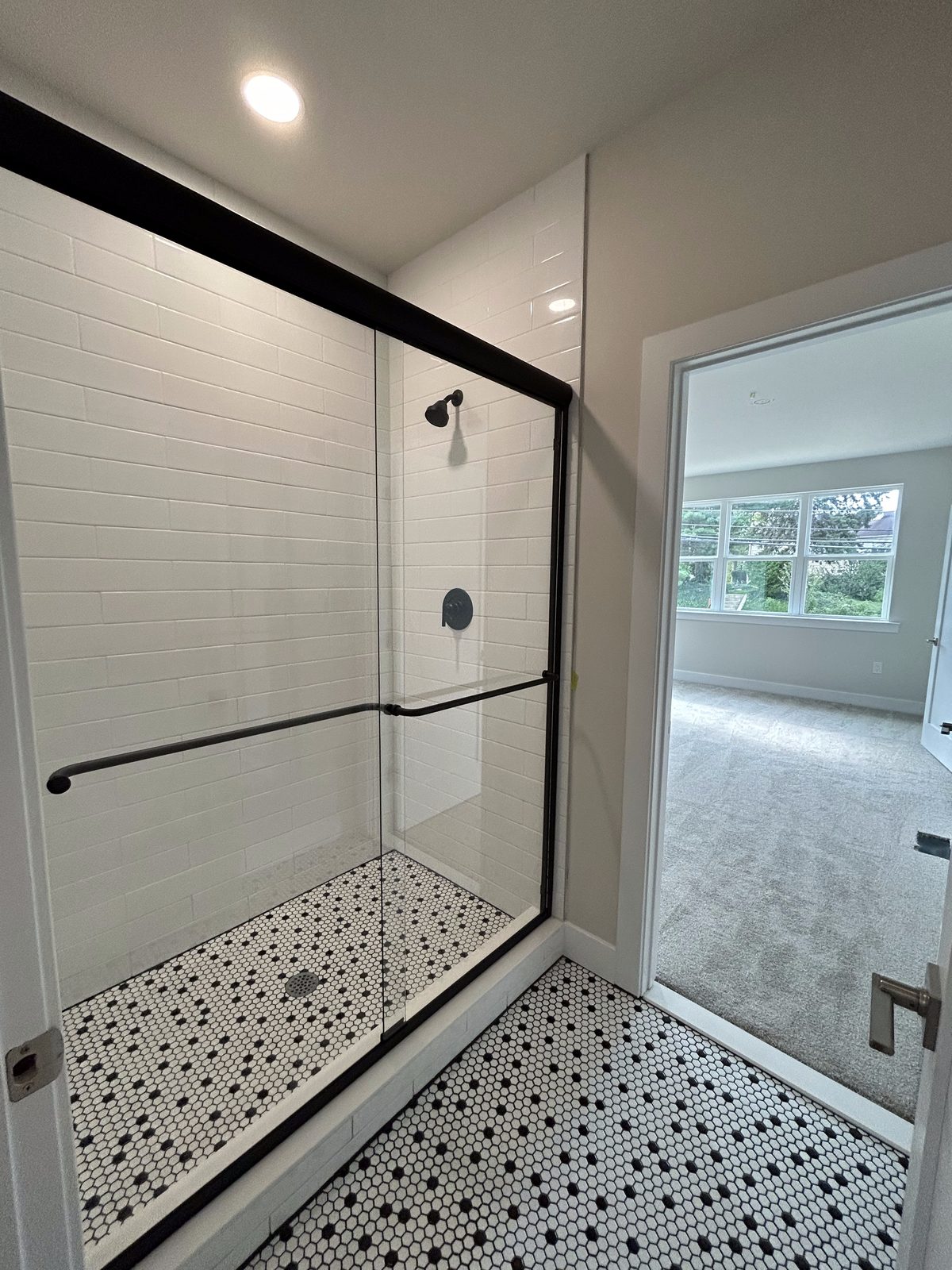 Model 1 guest suite bathroom glass shower with patterned tile floor
