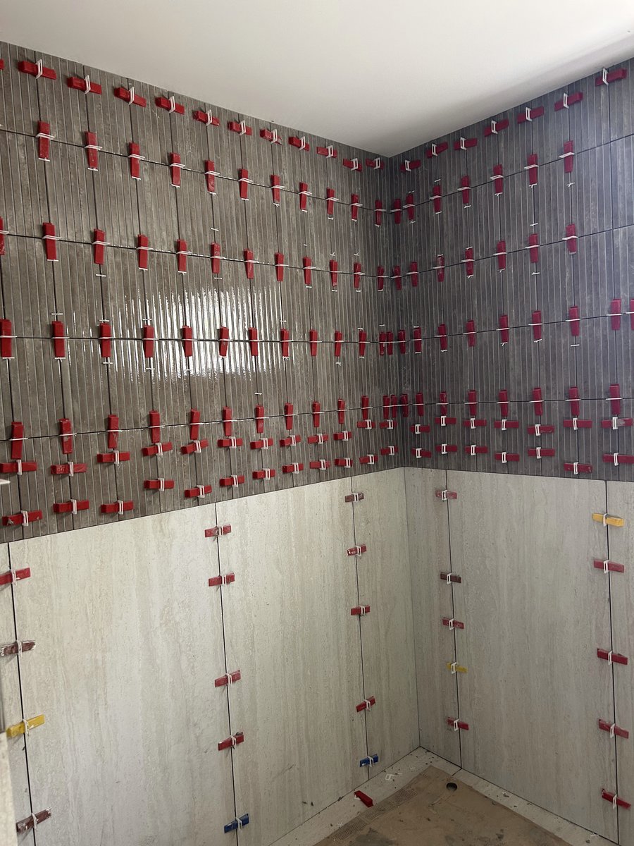Shower wall tile being set with leveling clips